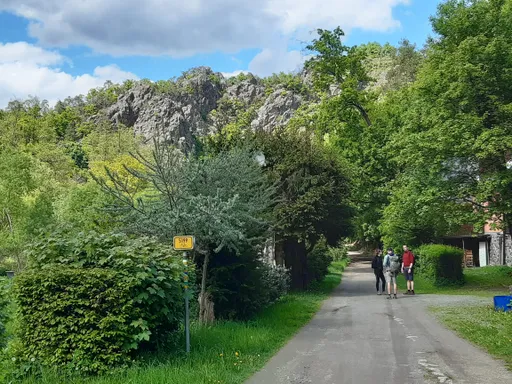 Silnička od Senoradské kantýny podél chat, nad ní skalní stěny a jarní zeleň
