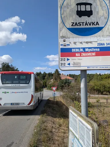 Autobusová zastávka Deblín, Myslivna u silnice, za ní odjíždějící autobus