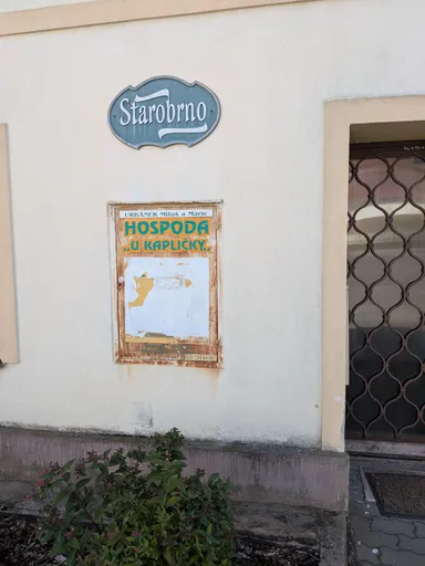 Vybledlá vývěska hospody U Kapličky pod cedulí Starobrno na fasádě