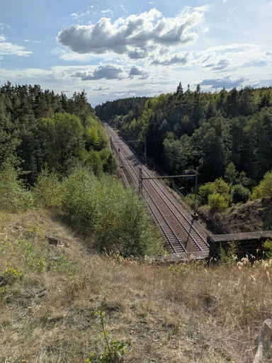 Pohled z výšky na železniční trať v zalesněném údolí