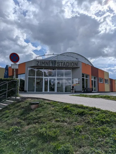 Vstup do nového zimního stadionu s obloukovou střechou a nápisem ZIMNÍ STADION.