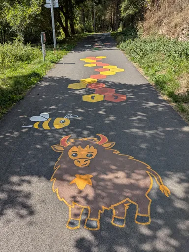 Na asfaltové cestě je namalovaná skákačka s obrázkem zubra a včely.