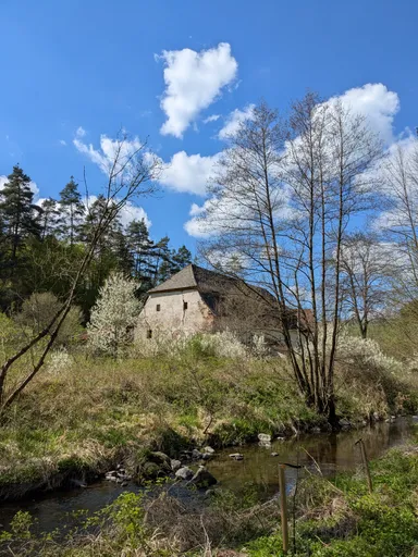 Starý kamenný mlýn s vysokým štítem nad potokem