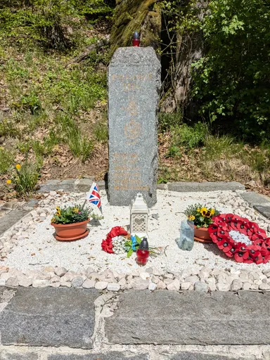 Pomník šesti britským vojákům s věnci vlčích máků a britskou vlajkou v údolí Oslavy.