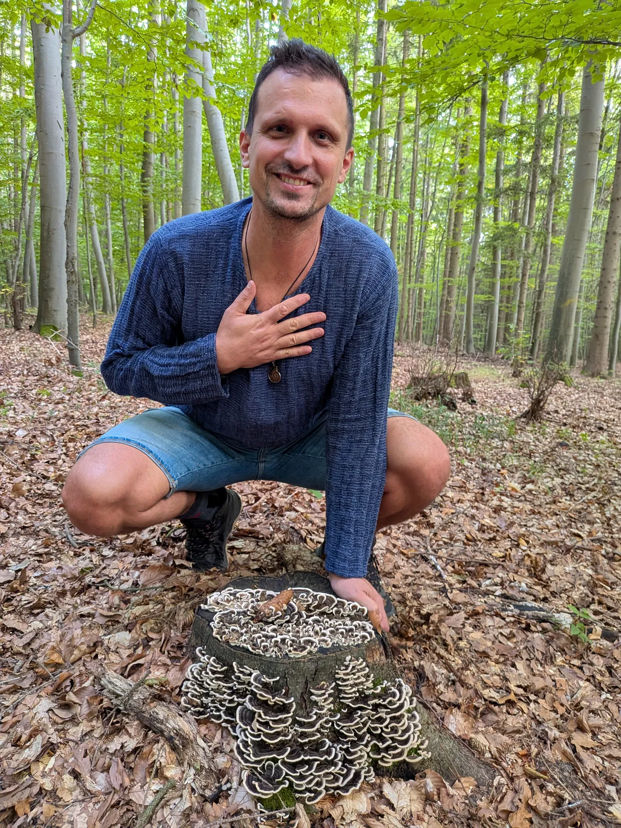 Dr. Houbička s rukou na srdci v podřepu u pařezu s outkovkou pestrou