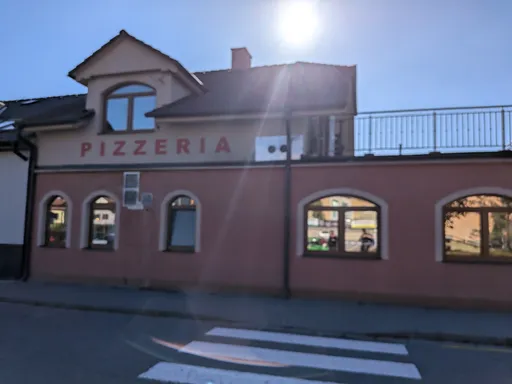 Růžová budova pizzerie Peperone s nápisem PIZZERIA a přechodem pro chodce v Náměšti nad Oslavou.