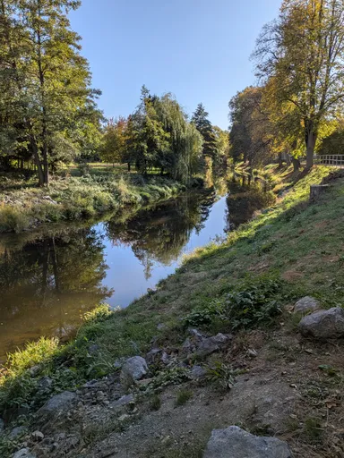 Řeka Oslava v Náměšti nad Oslavou mezi zelenými břehy a podzimními stromy.
