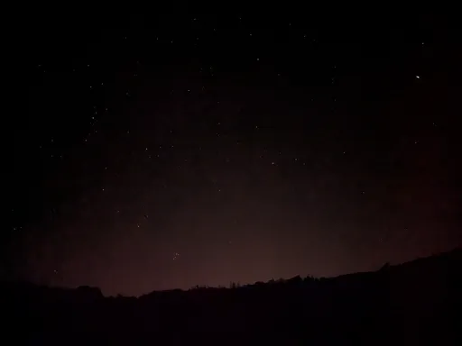 Noční obloha s hvězdami nad tmavým obrysem lesa v údolí Oslavy.