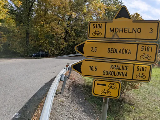 Žluté cyklistické směrovky na Mohelno, Sedlačku a Kralice u silnice.